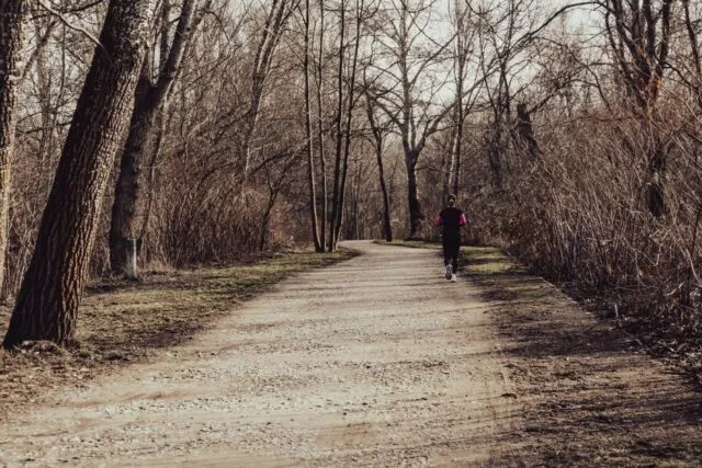 Alergător pe o alee acoperită de frunze, într-o dimineață de toamnă